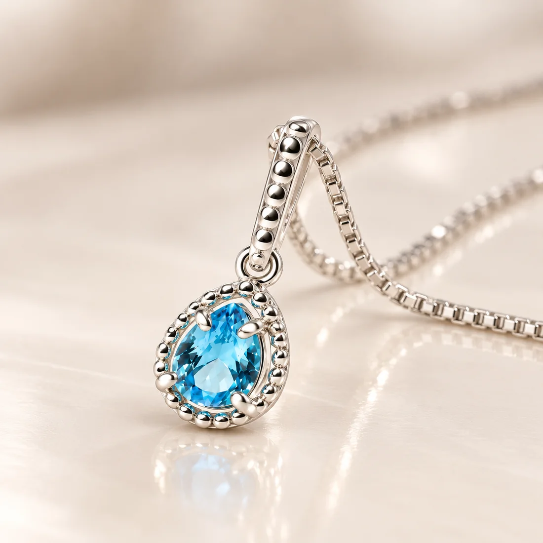 Detalhe de um colar com pedra azul em formato de gota e borda cravejada