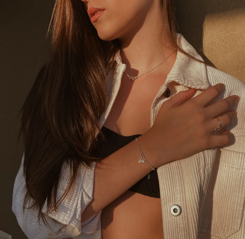 Modelo com joias da Leopoldina e camisa clara, em uma fotografia que destaca o colar e a pulseira